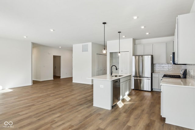 kitchen with an island with sink, stainless steel appliances, tasteful backsplash, pendant lighting, and sink