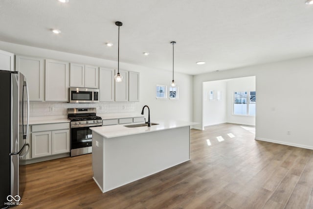 kitchen featuring sink, a wealth of natural light, hanging light fixtures, appliances with stainless steel finishes, and an island with sink