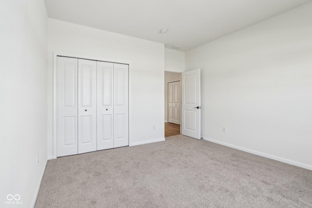 unfurnished bedroom with light carpet and a closet