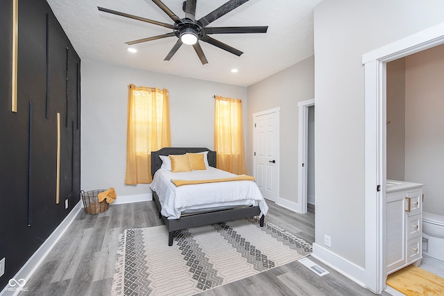 bedroom with ceiling fan, ensuite bath, a textured ceiling, and light hardwood / wood-style flooring