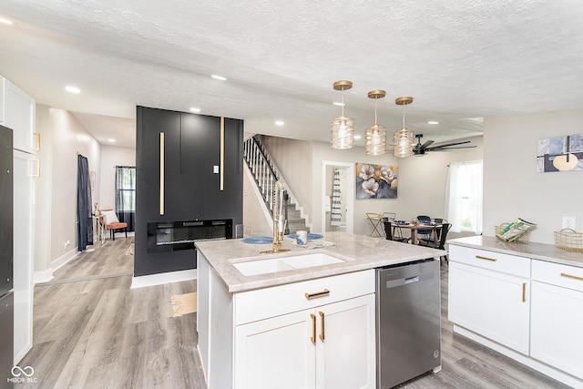 kitchen with light wood-type flooring, white cabinets, ceiling fan, pendant lighting, and dishwasher