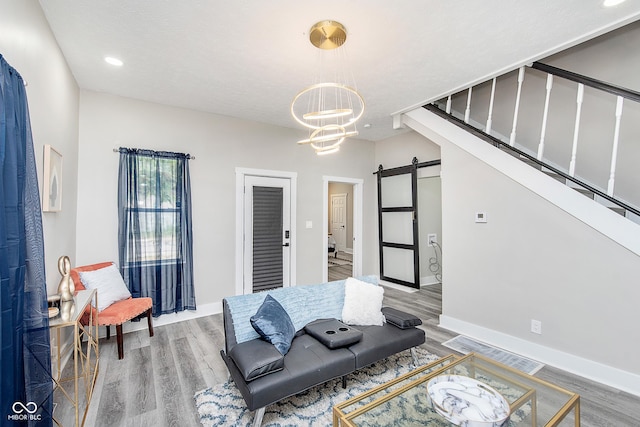 sitting room featuring a barn door, a chandelier, wood-type flooring, and a textured ceiling