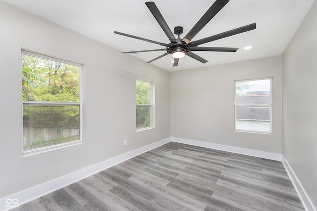 empty room with ceiling fan, plenty of natural light, and light hardwood / wood-style floors