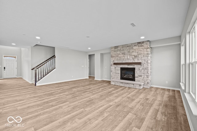 unfurnished living room featuring a stone fireplace and light hardwood / wood-style flooring