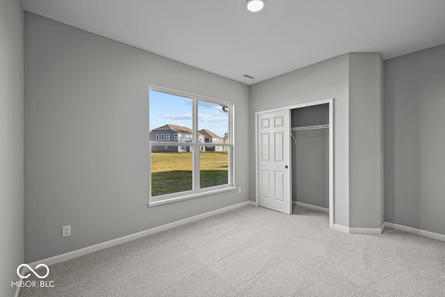 unfurnished bedroom featuring light colored carpet and a closet