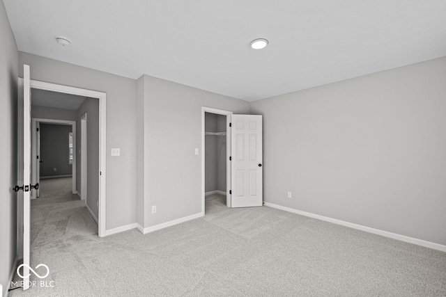 unfurnished bedroom with light colored carpet and a closet