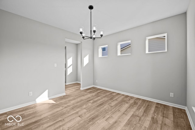 empty room with light wood-type flooring and an inviting chandelier