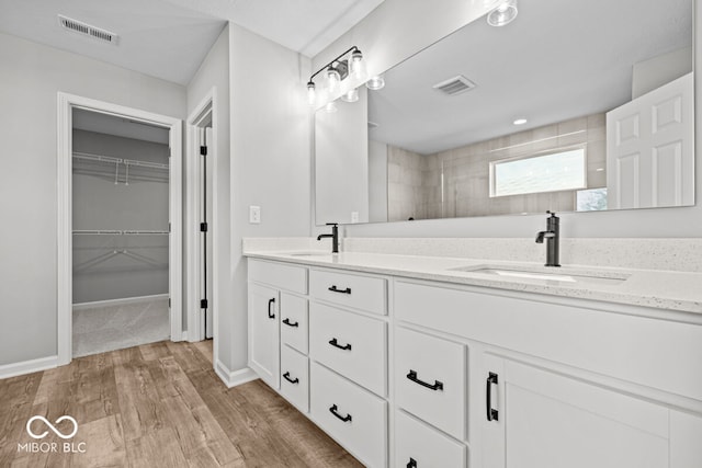 bathroom featuring hardwood / wood-style floors, vanity, and tiled shower