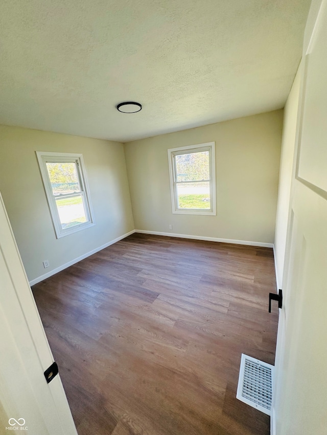 unfurnished room featuring hardwood / wood-style floors, a healthy amount of sunlight, and a textured ceiling