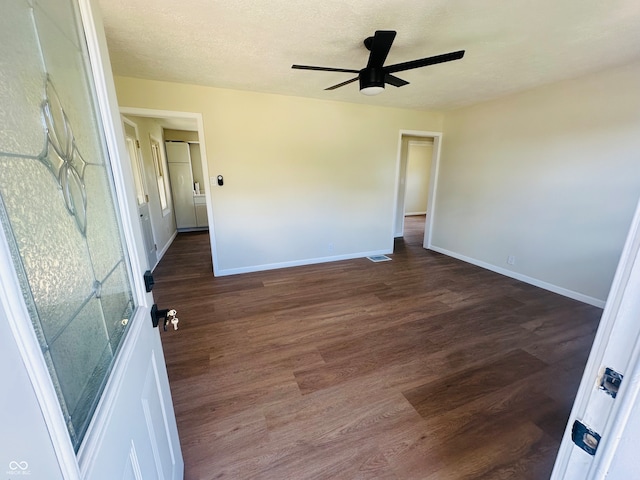 spare room featuring ceiling fan, dark wood-type flooring, and a textured ceiling