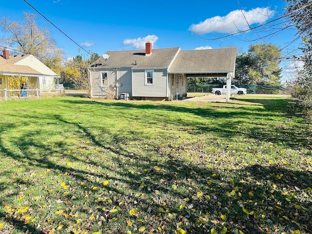 rear view of property featuring a lawn and a carport