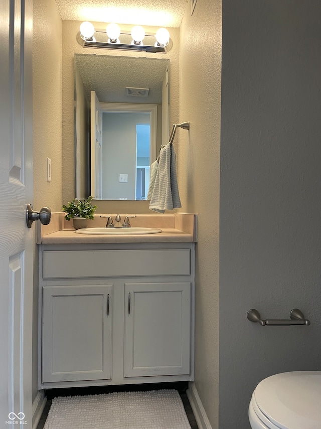 bathroom with vanity, a textured ceiling, and toilet