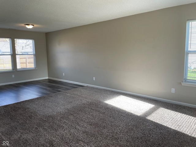 unfurnished room with dark hardwood / wood-style floors, a healthy amount of sunlight, and a textured ceiling