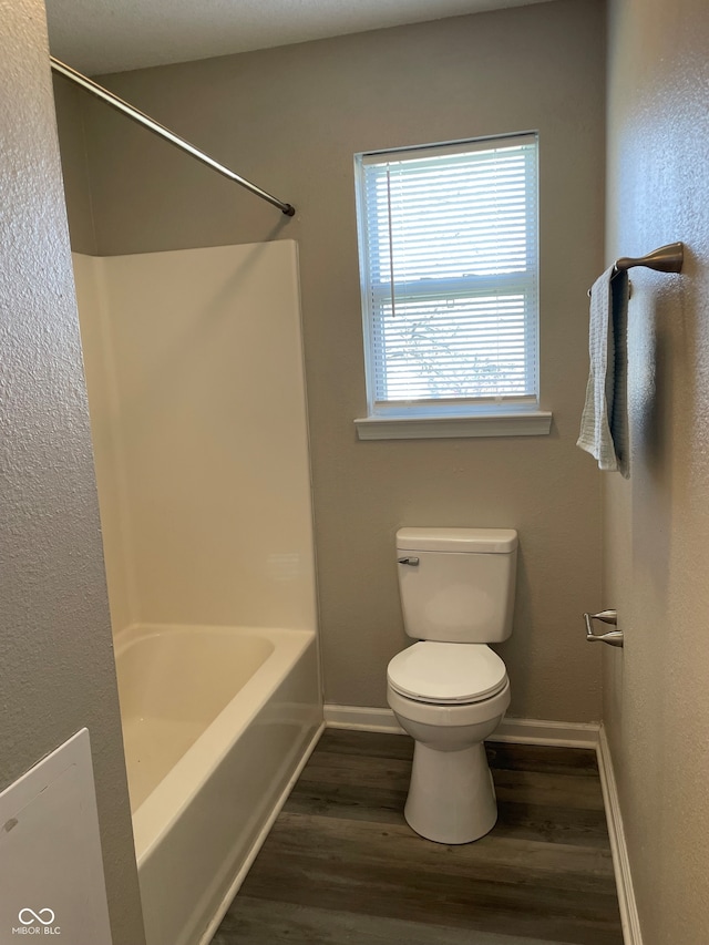 bathroom with hardwood / wood-style flooring, toilet, and shower / bathtub combination