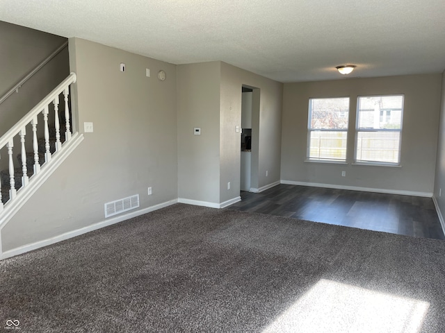 unfurnished living room with dark colored carpet and a textured ceiling