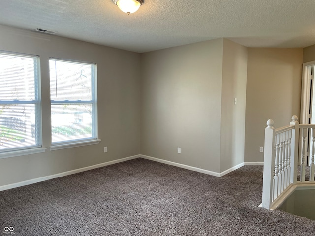 carpeted spare room with a textured ceiling