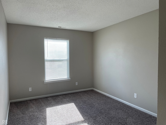 spare room featuring dark carpet and a textured ceiling