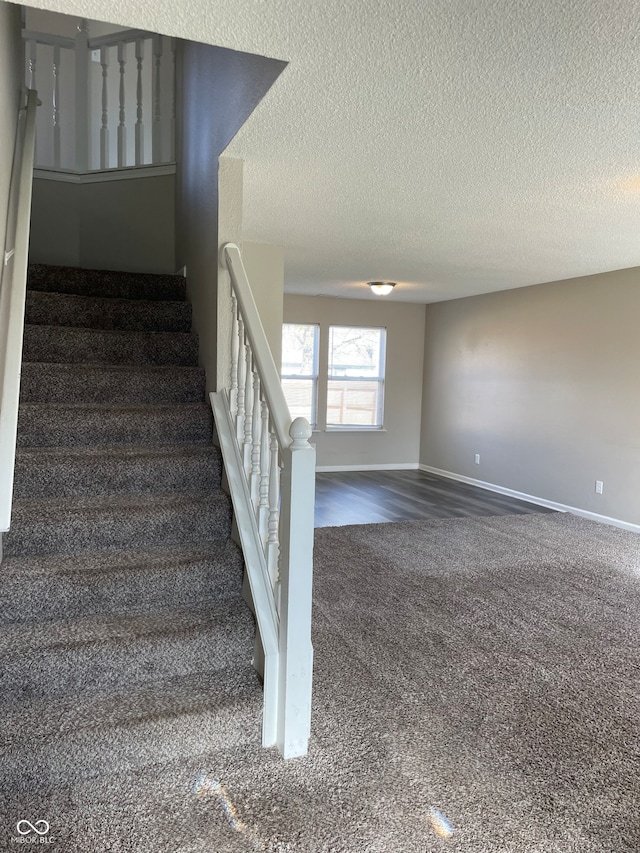 staircase with carpet flooring and a textured ceiling