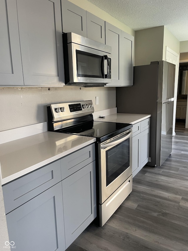 kitchen featuring light countertops, stainless steel appliances, dark wood-type flooring, gray cabinetry, and a textured ceiling