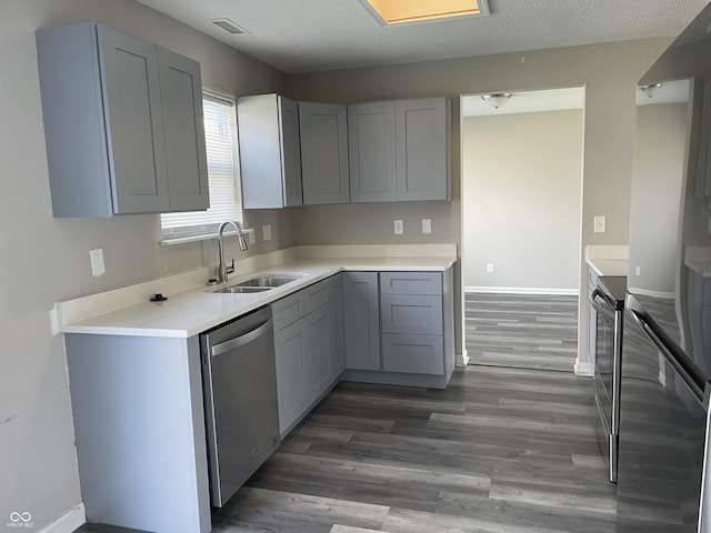 kitchen with a sink, wood finished floors, appliances with stainless steel finishes, and a textured ceiling