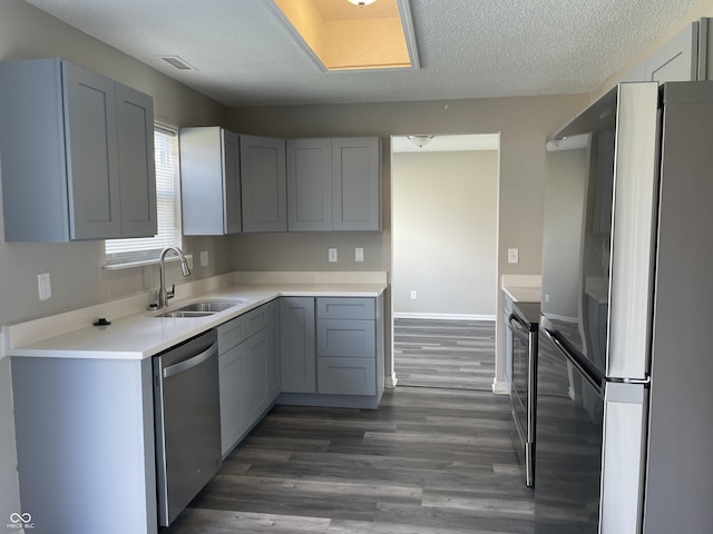 kitchen with a textured ceiling, visible vents, wood finished floors, stainless steel appliances, and a sink