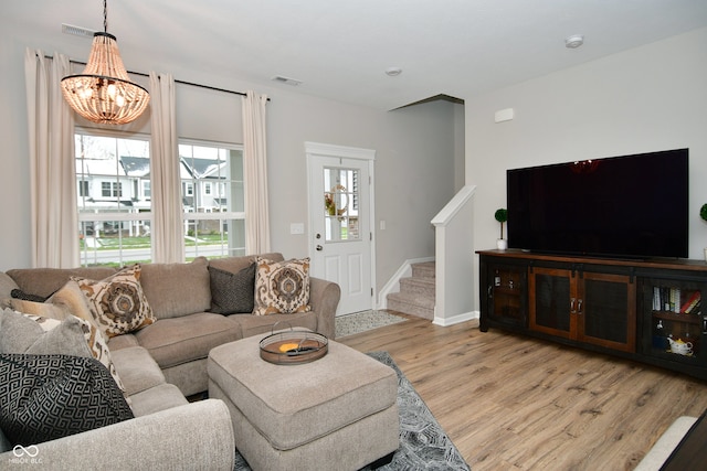 living room featuring light hardwood / wood-style flooring, a wealth of natural light, and a notable chandelier