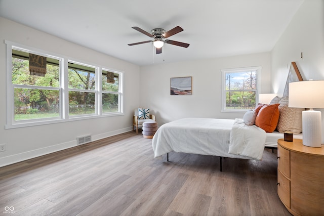 bedroom with multiple windows, ceiling fan, and hardwood / wood-style floors