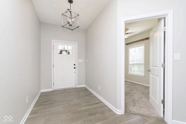 foyer entrance with ceiling fan with notable chandelier and wood-type flooring