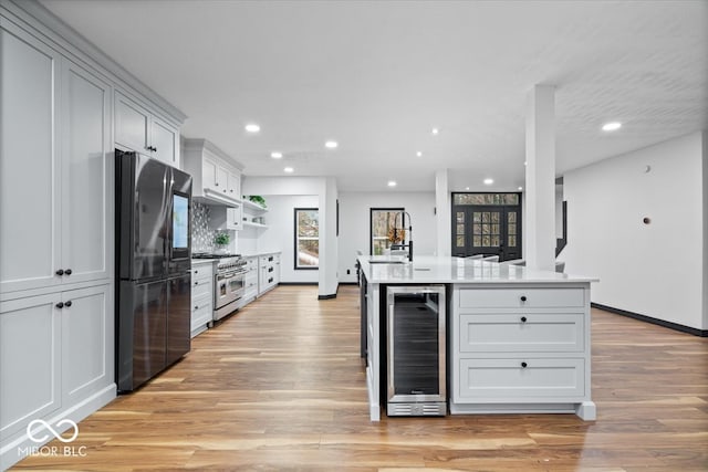 kitchen featuring stainless steel range, light hardwood / wood-style flooring, wine cooler, and fridge