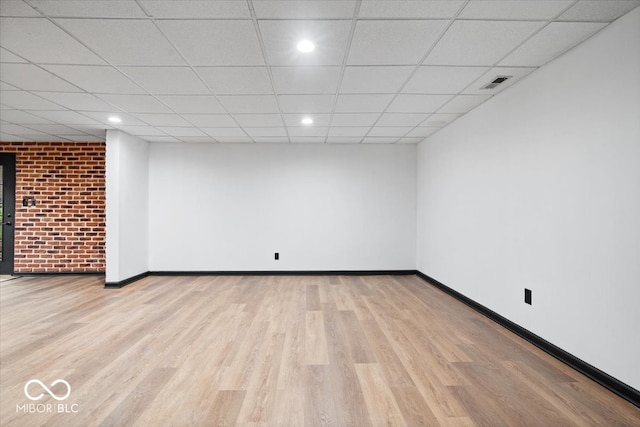 spare room featuring a paneled ceiling and light wood-type flooring