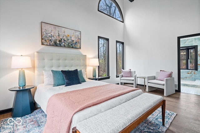 bedroom featuring hardwood / wood-style flooring, a high ceiling, and ensuite bath