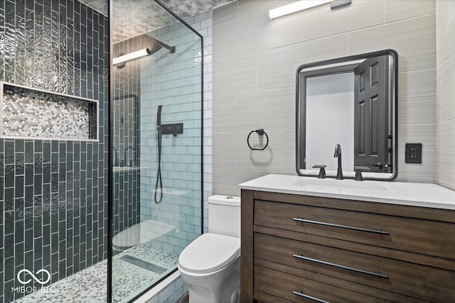 bathroom featuring toilet, a shower with door, and tile walls