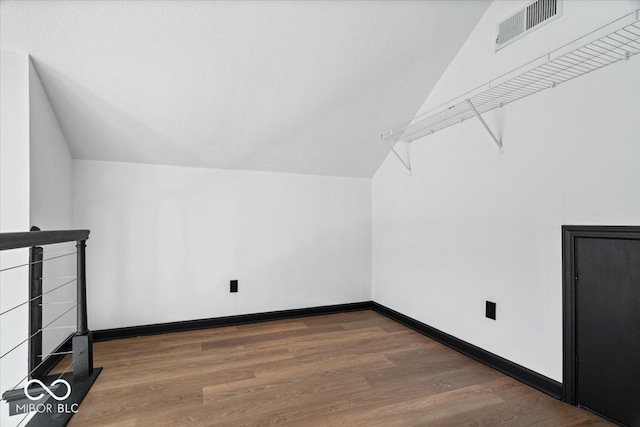 additional living space with dark wood-type flooring and vaulted ceiling