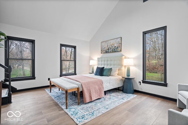 bedroom with light hardwood / wood-style flooring, high vaulted ceiling, and multiple windows