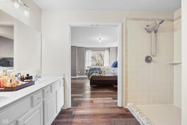 bathroom with hardwood / wood-style floors, vanity, and a tile shower