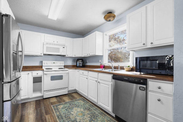 kitchen with wood counters, stainless steel appliances, white cabinetry, and sink