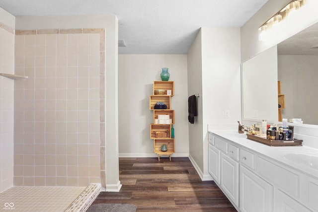 bathroom featuring vanity, wood-type flooring, a textured ceiling, and tiled shower