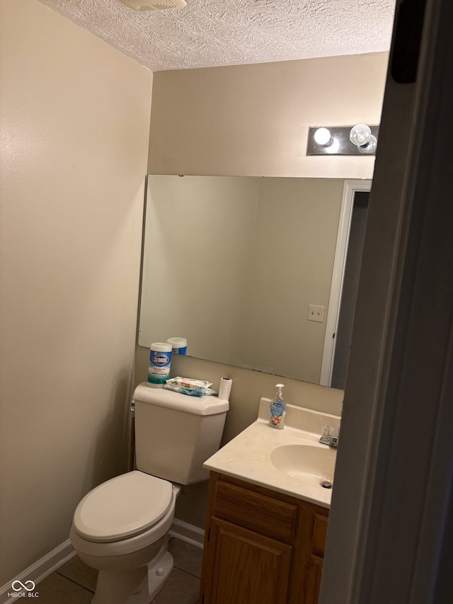 bathroom featuring tile patterned floors, vanity, a textured ceiling, and toilet