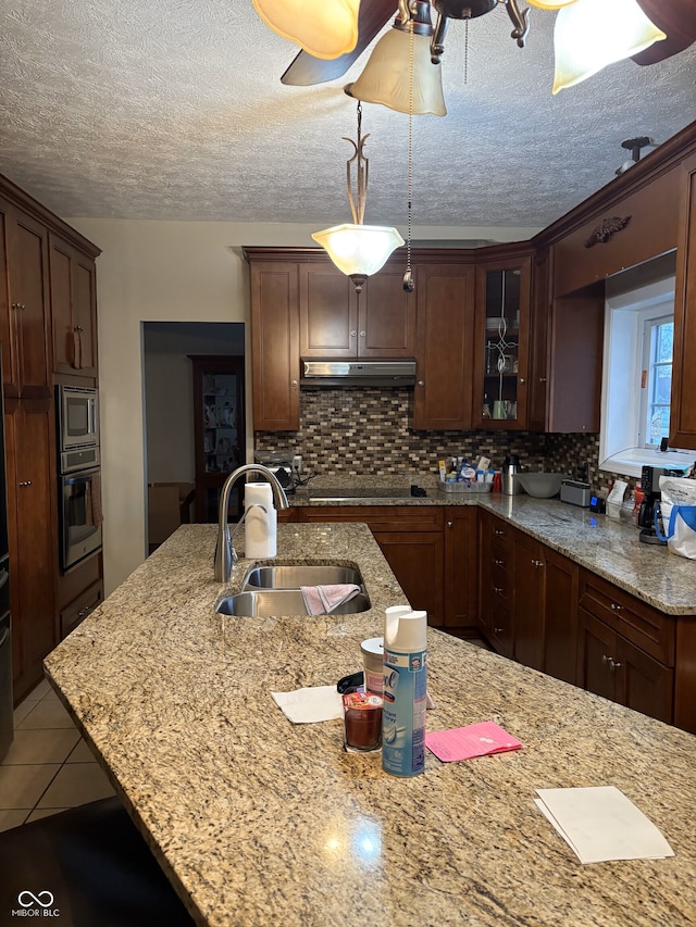 kitchen featuring decorative backsplash, a textured ceiling, stainless steel appliances, sink, and hanging light fixtures