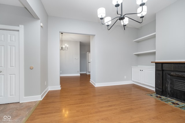 unfurnished living room with an inviting chandelier and light wood-type flooring