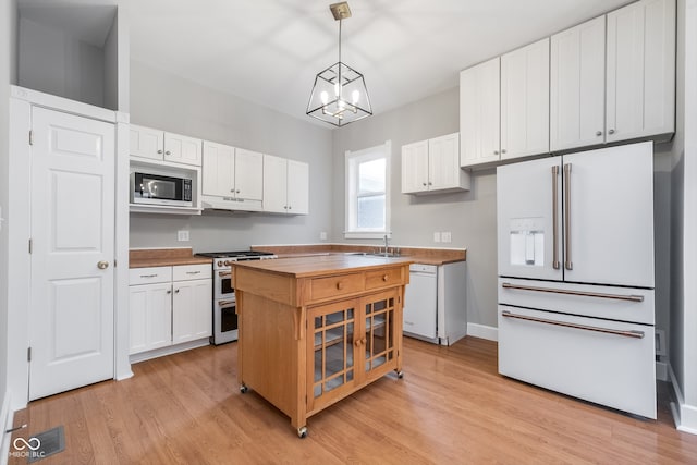 kitchen with light hardwood / wood-style flooring, appliances with stainless steel finishes, decorative light fixtures, a kitchen island, and white cabinetry