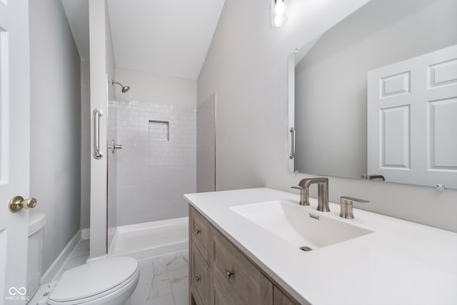 bathroom with a tile shower, vanity, and toilet