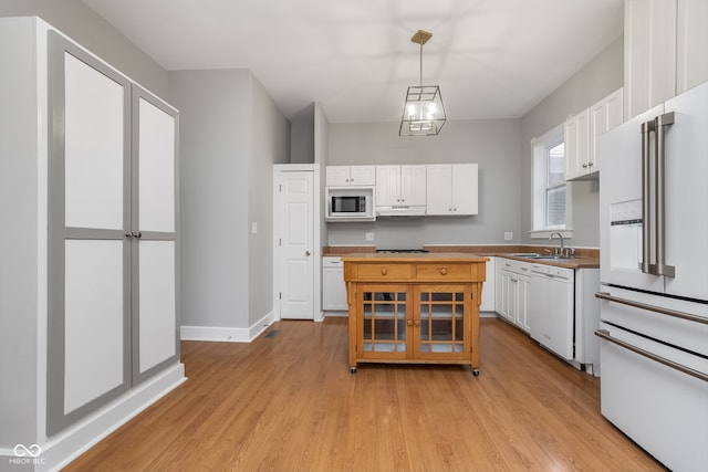 kitchen featuring white appliances, sink, light hardwood / wood-style floors, white cabinetry, and hanging light fixtures