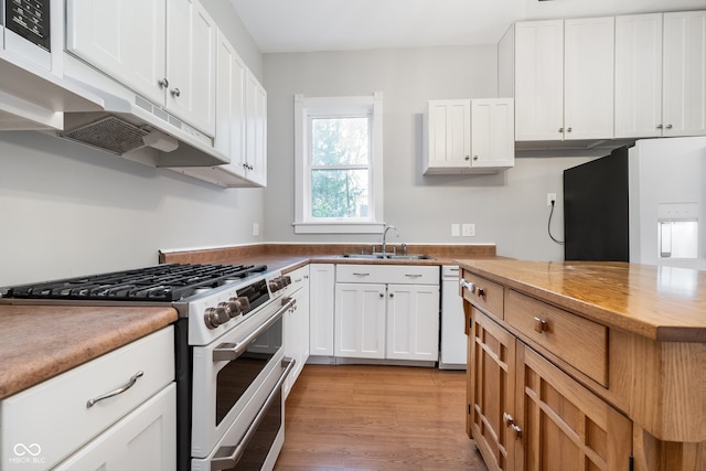 kitchen with high end range, sink, light hardwood / wood-style flooring, dishwasher, and white cabinets