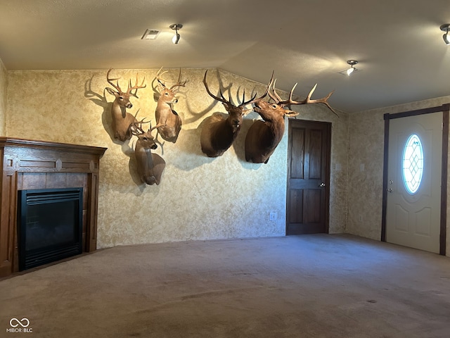 interior space with a tiled fireplace, carpet, and lofted ceiling