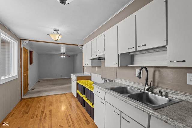 kitchen featuring sink, light wood-type flooring, white cabinetry, ceiling fan, and tasteful backsplash