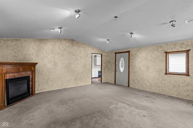 unfurnished living room with a tile fireplace, carpet flooring, and lofted ceiling