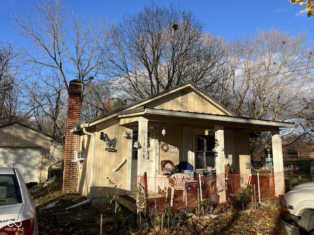 view of side of property with covered porch, a garage, and an outdoor structure