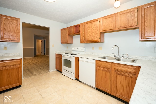 kitchen with a textured ceiling, white appliances, light hardwood / wood-style flooring, and sink