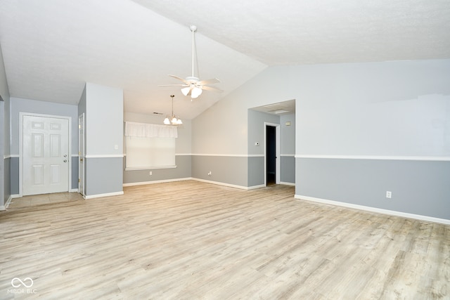 spare room featuring ceiling fan with notable chandelier, lofted ceiling, and light wood-type flooring